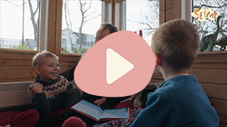 Voksen mann som leser en bok for to barn