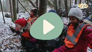 Barn som leker ute i skogen på vinterstid